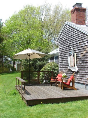 The back deck with lots of lawn and art around in Barnstable, Cummaquid Mid Cape Cod